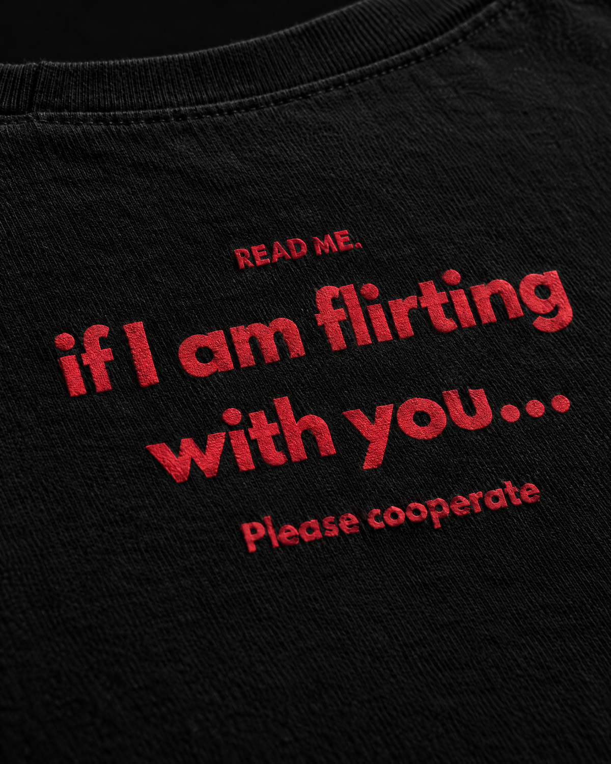 Dettaglio della stampa rossa Read Me sulla t-shirt nera