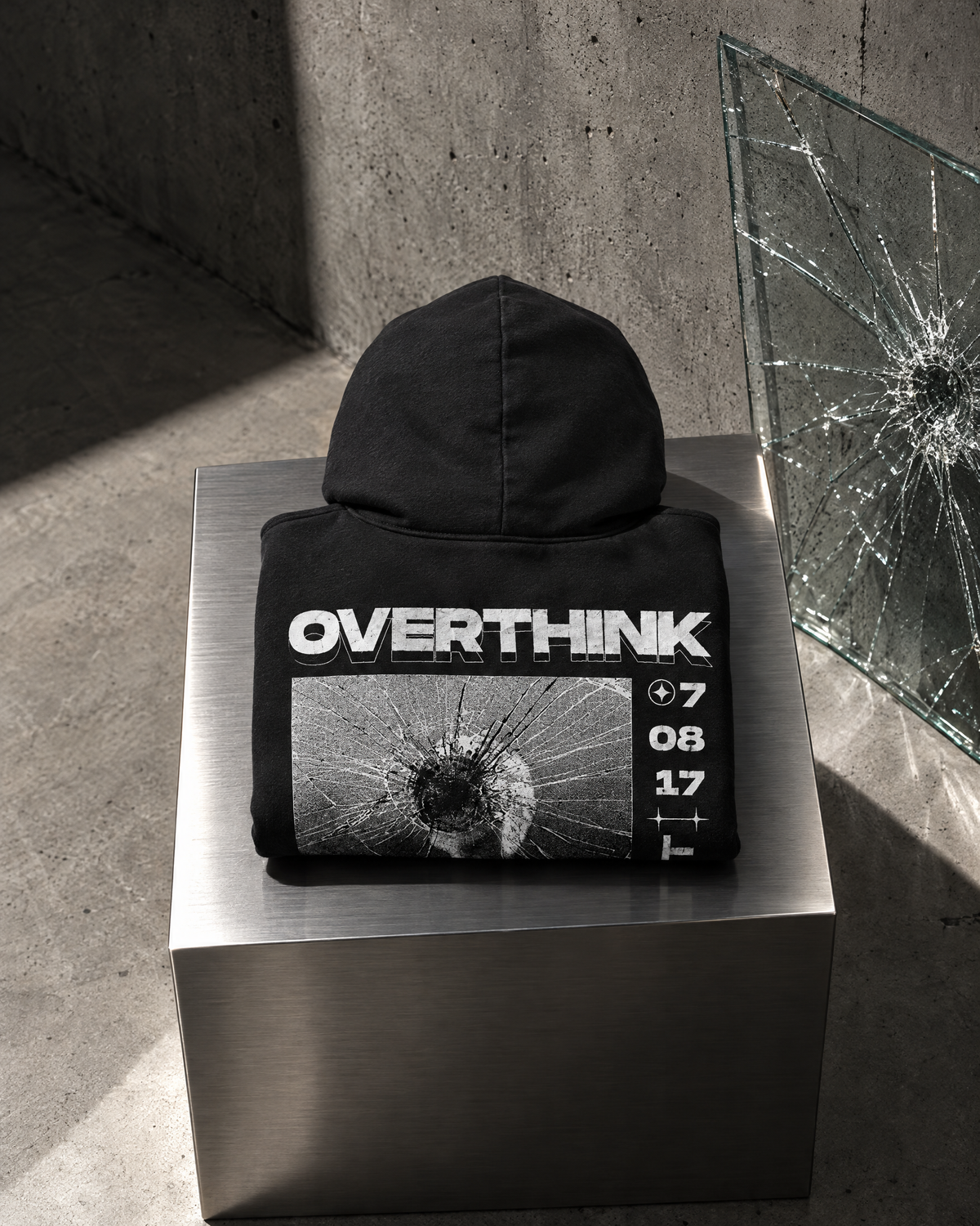 Felpa Overthink nera piegata su cubo in acciaio, stampa sul retro
